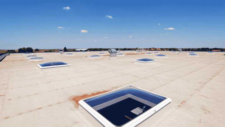 A large flat roof with aging TPO roofing installed on it.