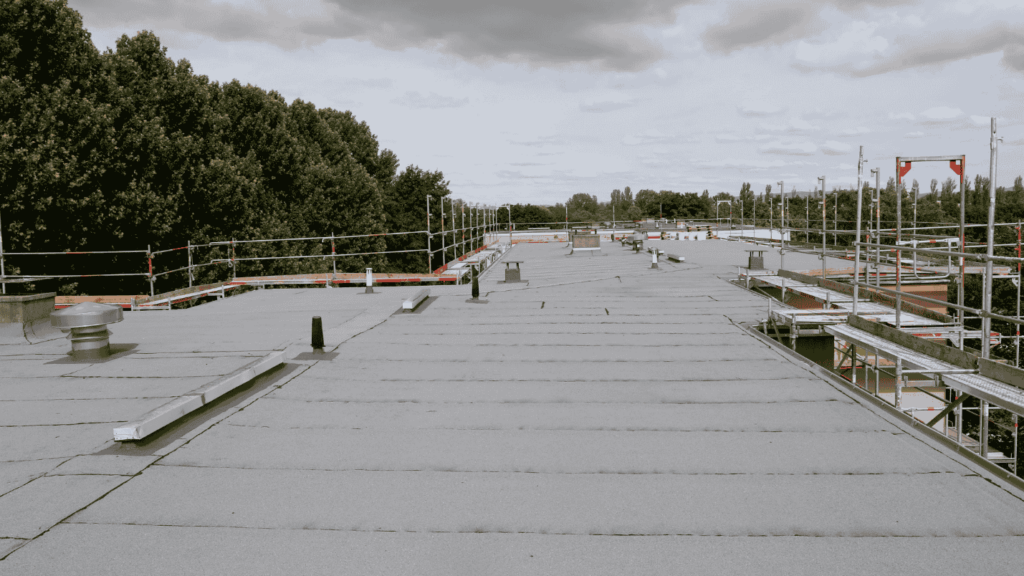 A large home surrounded by trees that is getting a flat roof replacement.