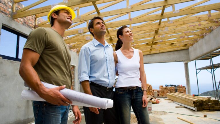 A roofing contractor examines a roof with two clients.